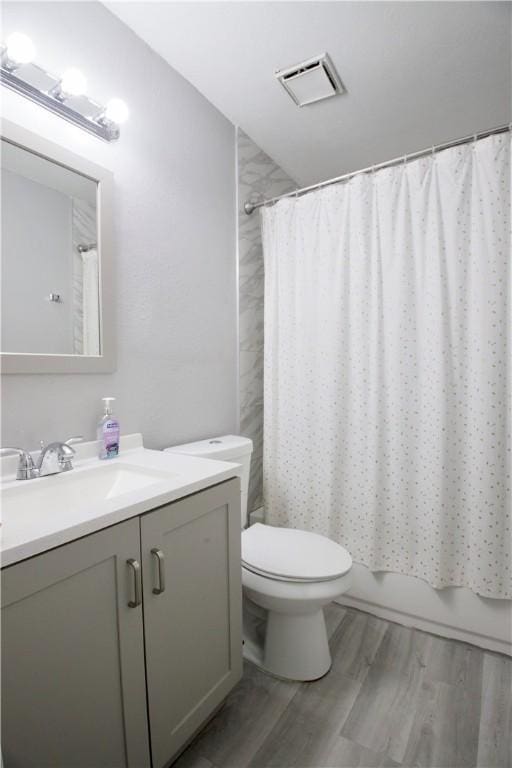 full bathroom with hardwood / wood-style flooring, vanity, shower / tub combo, and toilet