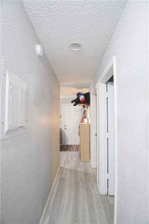 hall featuring light hardwood / wood-style floors and a textured ceiling