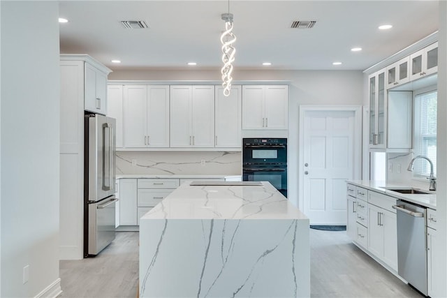 kitchen featuring decorative light fixtures, sink, white cabinets, and stainless steel appliances