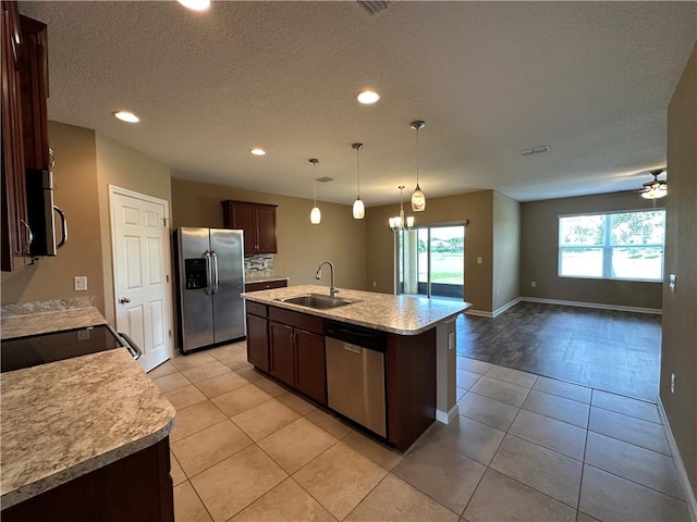 3315 Rockport St SW, Vero Beach, FL 32968 - kitchen with stainless steel appliances, light tile patterned floors, dark brown cabinetry, light countertops, and a kitchen island with sink