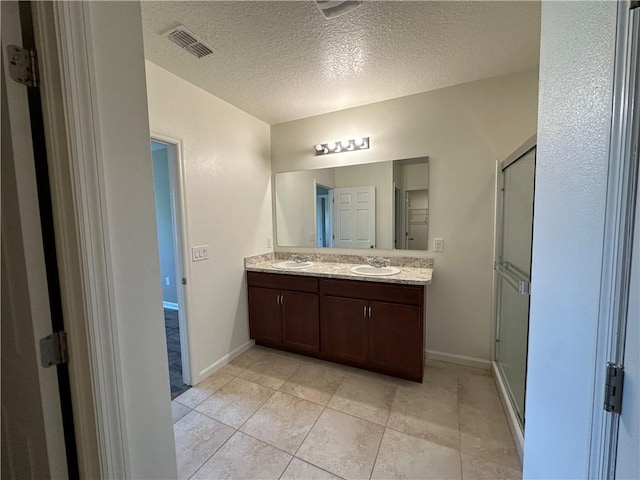 3315 Rockport St SW, Vero Beach, FL 32968 - bathroom featuring double vanity, a textured ceiling, a shower stall, and tile patterned floors