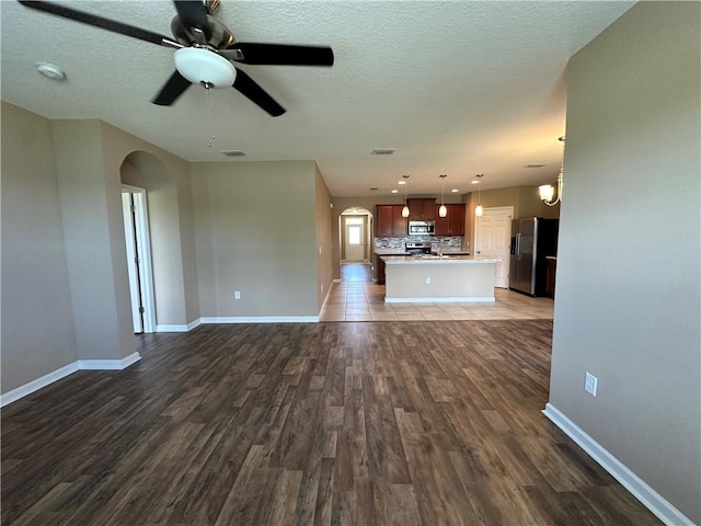 3315 Rockport St SW, Vero Beach, FL 32968 - unfurnished living room with arched walkways, dark wood-style floors, ceiling fan, and a textured ceiling