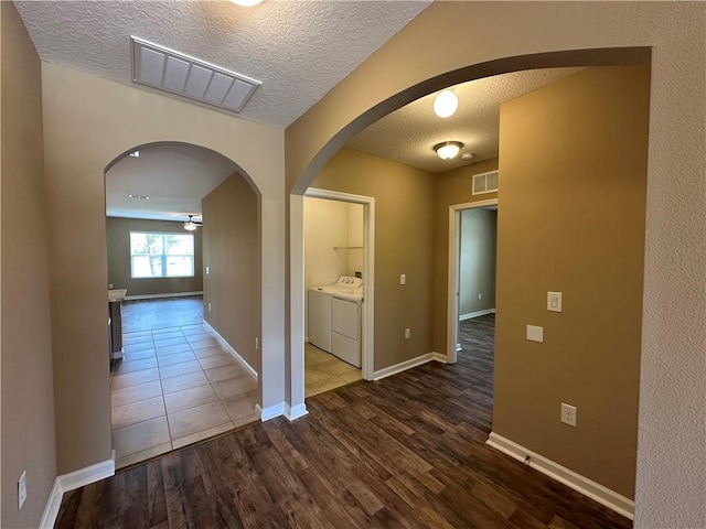 3315 Rockport St SW, Vero Beach, FL 32968 - hall featuring washer and clothes dryer, a textured ceiling, wood finished floors, and arched walkways