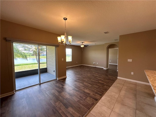 3315 Rockport St SW, Vero Beach, FL 32968 - spare room with arched walkways, dark wood-style flooring, a textured ceiling, a ceiling fan, and a chandelier