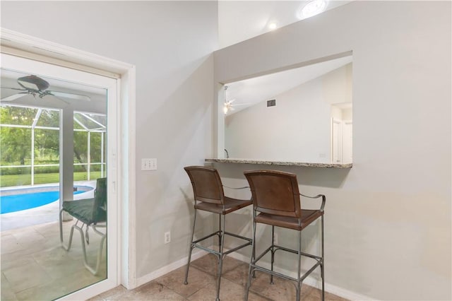 tiled dining area with lofted ceiling, a sunroom, ceiling fan, and baseboards