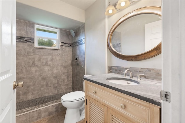 bathroom featuring toilet, backsplash, tiled shower, and vanity