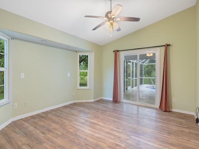 unfurnished room featuring vaulted ceiling, plenty of natural light, a ceiling fan, and light wood-style floors