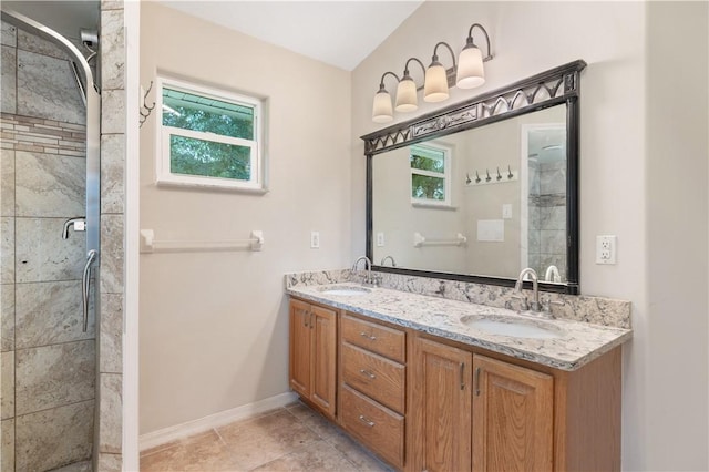 full bath featuring a sink, a tile shower, baseboards, and double vanity