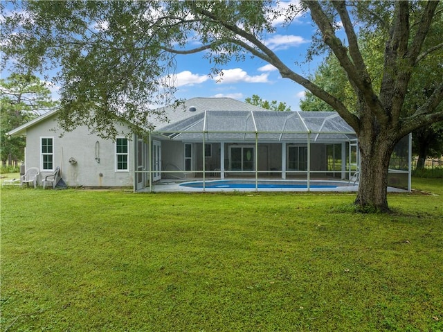 rear view of property featuring glass enclosure and a lawn