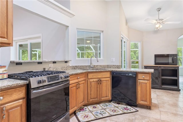 kitchen with black appliances, sink, ceiling fan, kitchen peninsula, and light stone counters