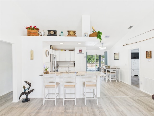 7965 105th Ave, Vero Beach, FL 32967 - kitchen with stainless steel fridge, a peninsula, light countertops, a kitchen breakfast bar, and high vaulted ceiling
