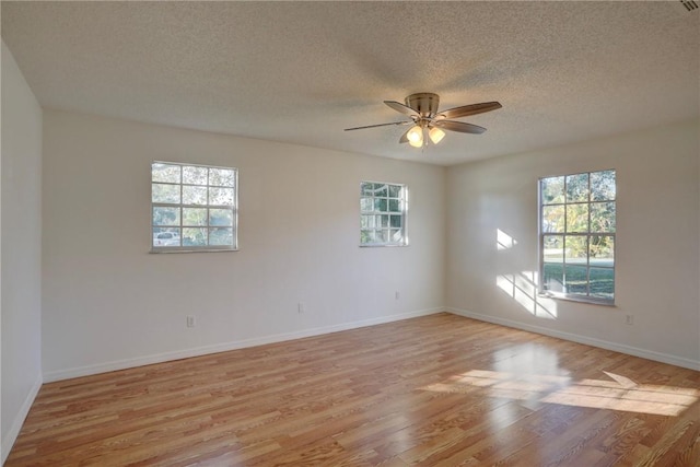 spare room featuring baseboards, ceiling fan, light wood-type flooring, and plenty of natural light