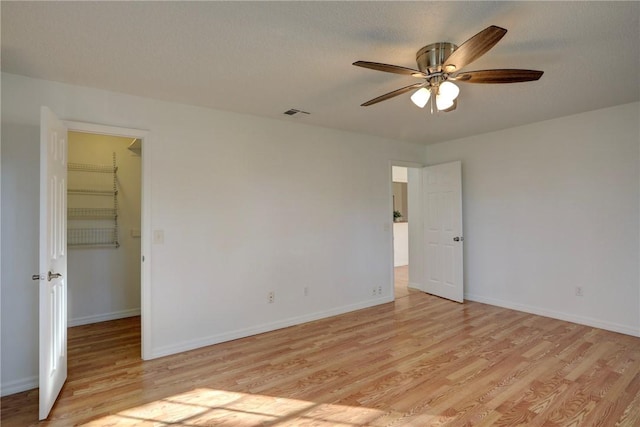 empty room featuring light wood finished floors, baseboards, visible vents, and ceiling fan