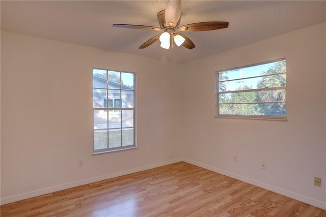empty room featuring plenty of natural light, baseboards, and light wood-style floors
