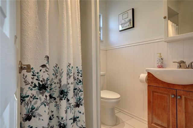 bathroom with tile patterned flooring, vanity, toilet, a wainscoted wall, and curtained shower