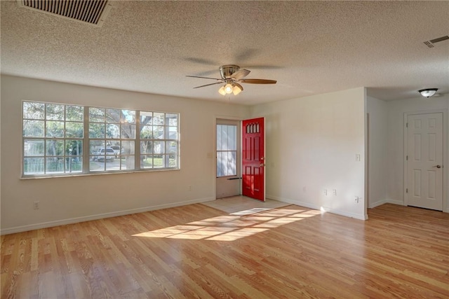 empty room with ceiling fan, visible vents, light wood-style floors, and plenty of natural light