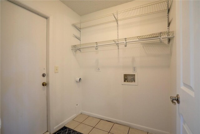 laundry area featuring hookup for a washing machine, baseboards, laundry area, electric dryer hookup, and light tile patterned floors