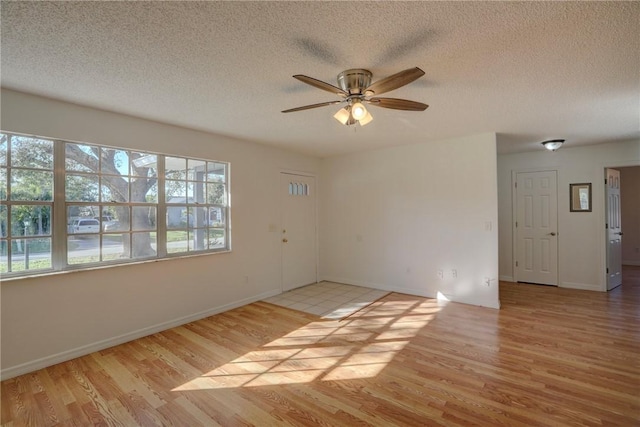 empty room featuring a ceiling fan, a textured ceiling, and wood finished floors