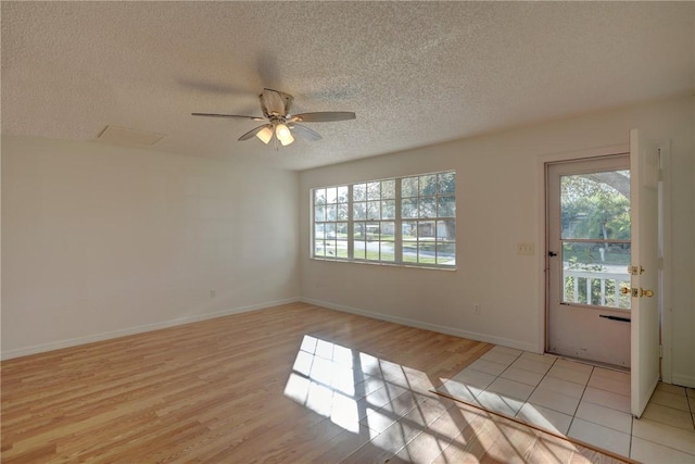 unfurnished room featuring light wood-style flooring, plenty of natural light, and a textured ceiling