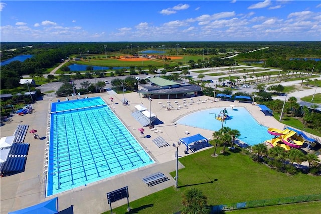 community pool featuring a water view, fence, and a patio