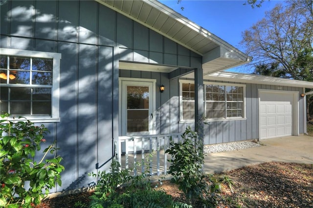 doorway to property featuring a garage, board and batten siding, and concrete driveway