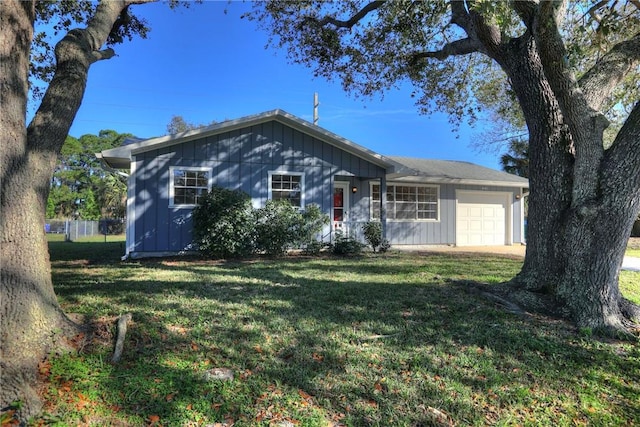 single story home featuring a front lawn, an attached garage, and board and batten siding