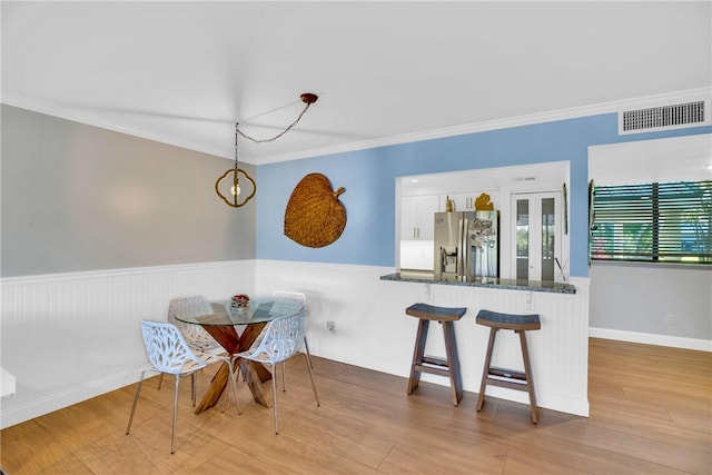 dining area featuring light wood-type flooring, crown molding, and an inviting chandelier