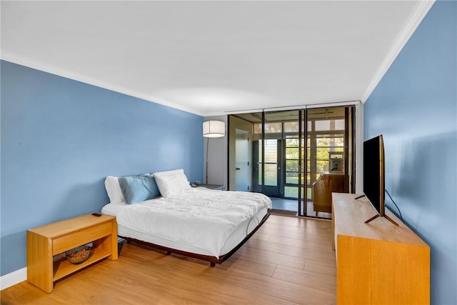 bedroom featuring access to exterior, crown molding, hardwood / wood-style floors, and a wall of windows