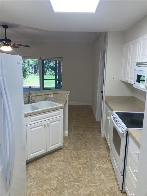 kitchen with white appliances, ceiling fan, a sink, light countertops, and white cabinetry