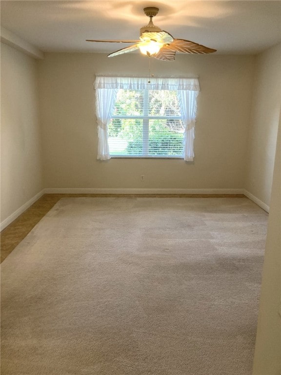 carpeted empty room featuring baseboards and a ceiling fan