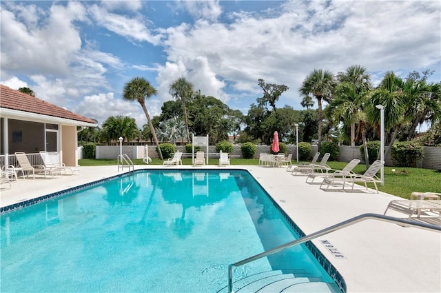 community pool with a patio and fence