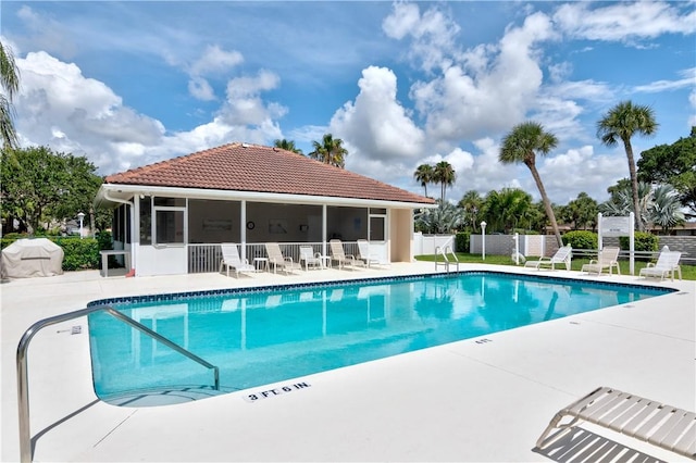 pool with a patio, fence, and a sunroom