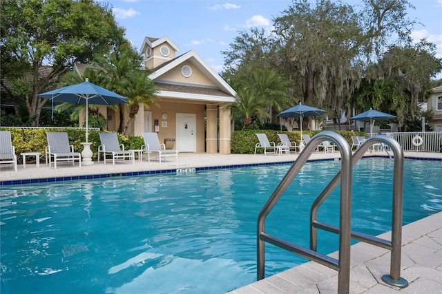 community pool with a patio area and fence