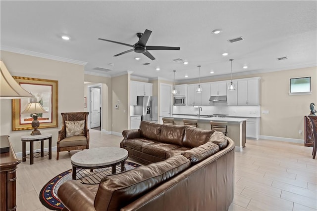 living area with baseboards, visible vents, a ceiling fan, and ornamental molding