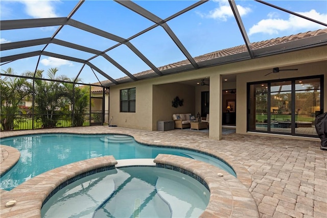 view of pool with a lanai, outdoor lounge area, a pool with connected hot tub, a ceiling fan, and a patio area