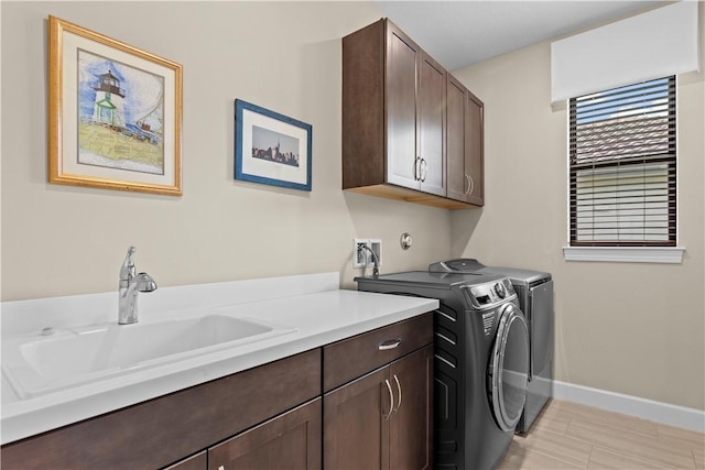 clothes washing area featuring independent washer and dryer, a sink, cabinet space, and baseboards