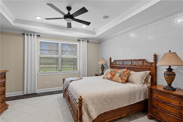 bedroom featuring baseboards, brick wall, a tray ceiling, and crown molding