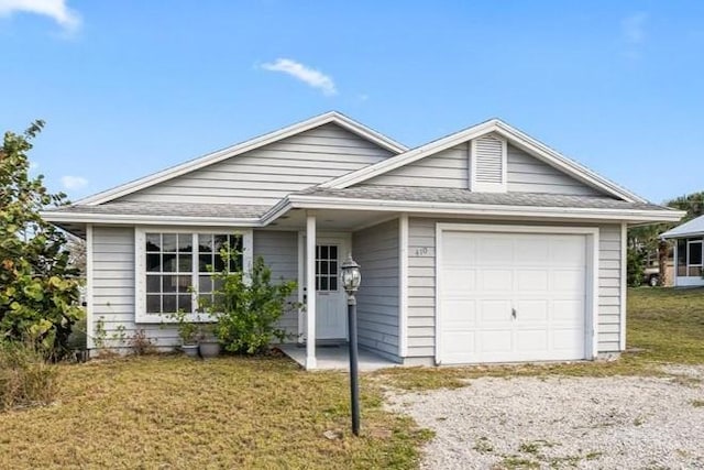 single story home featuring an attached garage, gravel driveway, and a front yard