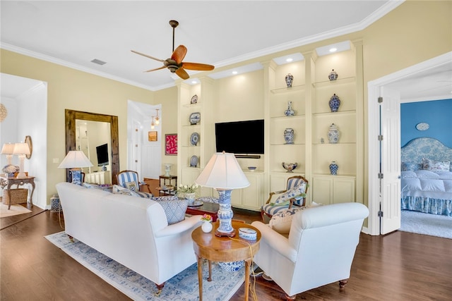 living room with dark hardwood / wood-style flooring, ceiling fan, ornamental molding, and built in shelves