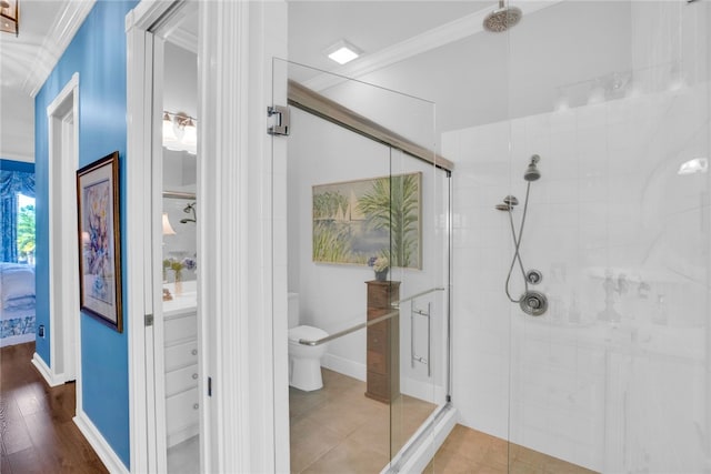 bathroom featuring hardwood / wood-style flooring, a shower with door, toilet, and crown molding