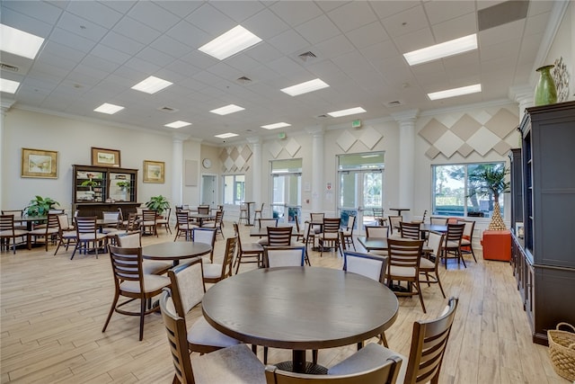 dining room with decorative columns, a paneled ceiling, light wood-type flooring, and ornamental molding