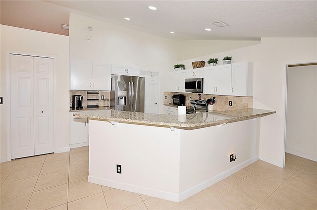 kitchen with stainless steel appliances, decorative backsplash, vaulted ceiling, white cabinets, and kitchen peninsula