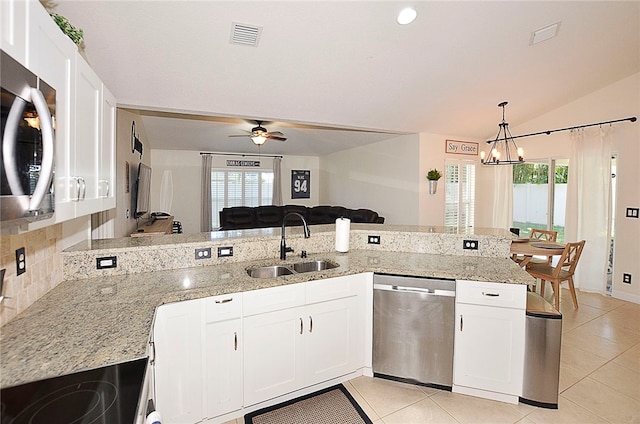 kitchen featuring stainless steel appliances, light stone counters, vaulted ceiling, sink, and white cabinetry