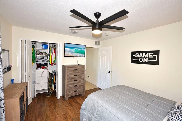 bedroom with dark wood-type flooring, a closet, a textured ceiling, and ceiling fan