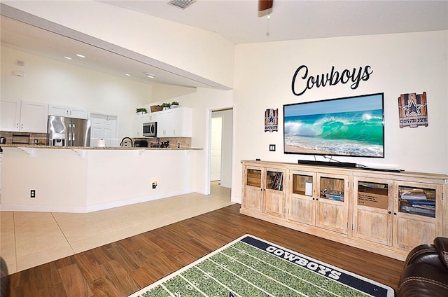 living room featuring lofted ceiling, hardwood / wood-style floors, and ceiling fan