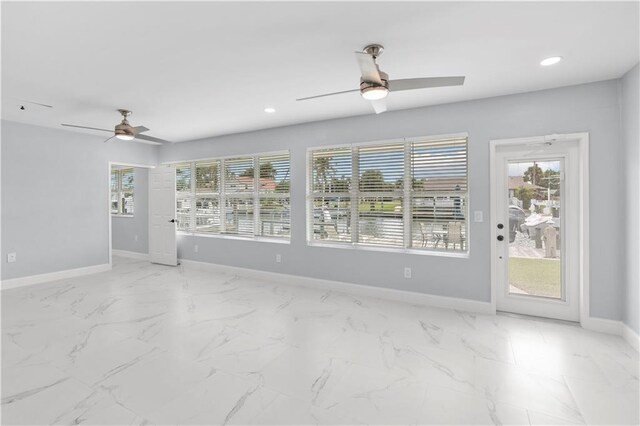 empty room featuring ceiling fan and a wealth of natural light