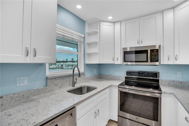 kitchen with light stone counters, white cabinetry, sink, and appliances with stainless steel finishes