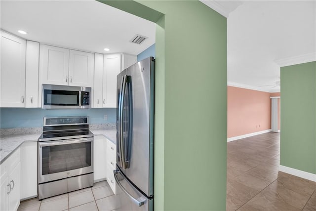 kitchen featuring light stone counters, ornamental molding, stainless steel appliances, light tile patterned floors, and white cabinetry