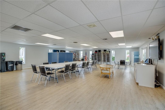 dining space with light wood-type flooring and a paneled ceiling