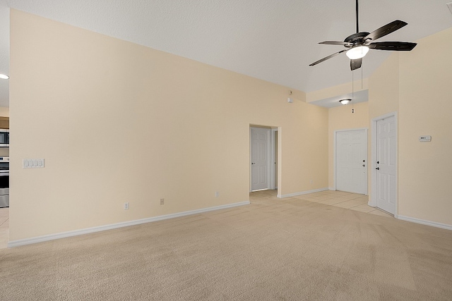 empty room with ceiling fan, light colored carpet, and high vaulted ceiling